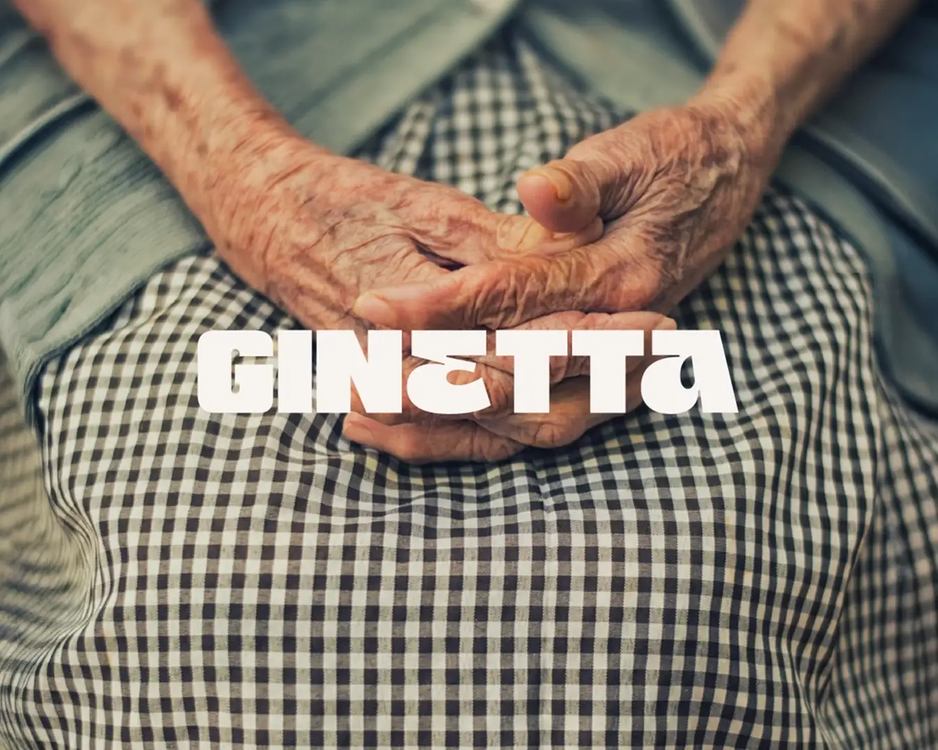 Branding Ginetta - Mains croisées d'une grand-mère italienne sur sa jupe en vichy, symbole de transmission et d'authenticité