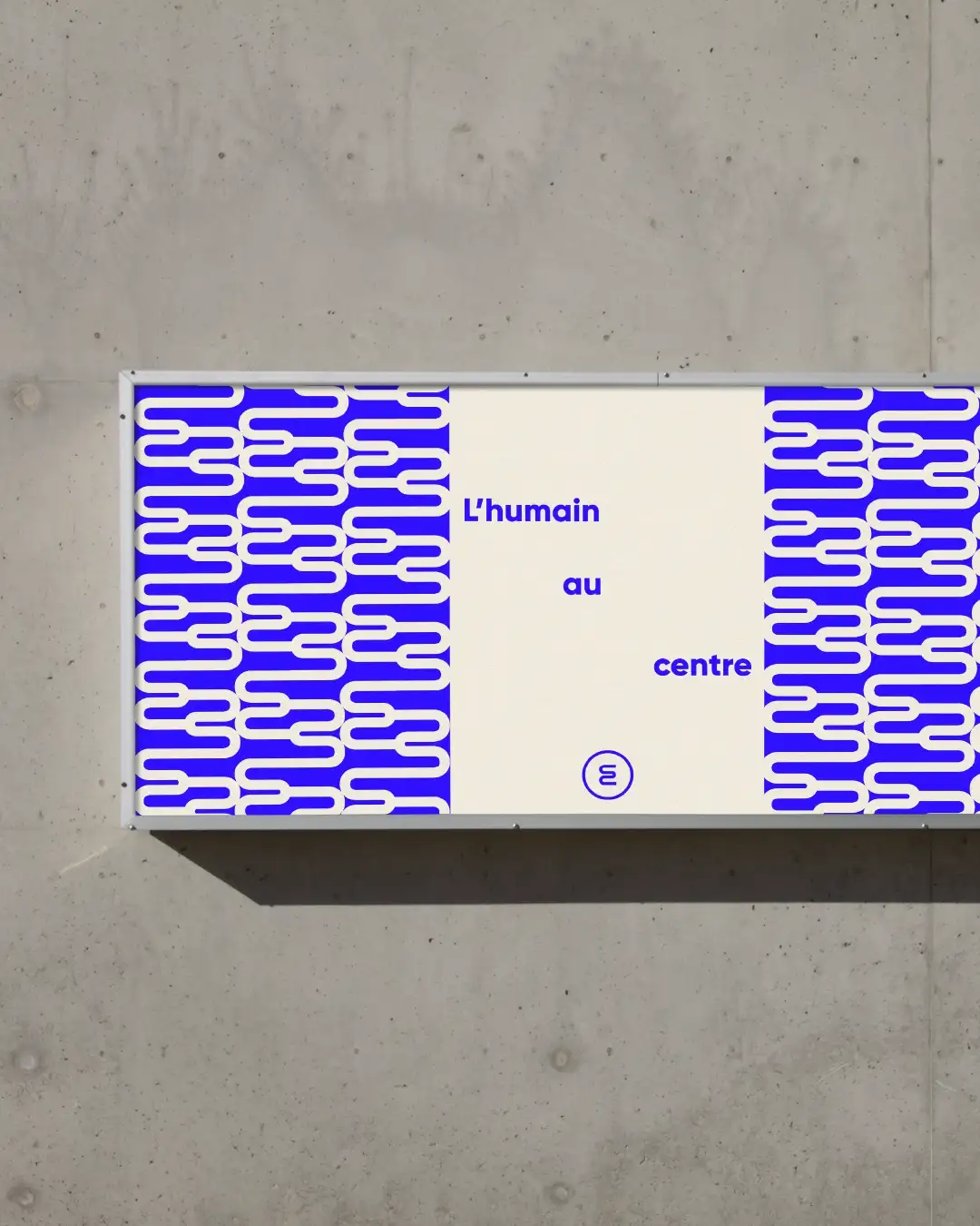 CED triptych billboard on raw concrete wall: pattern left, "Human-centered" baseline with monogram center, pattern right, cream and Klein blue palette, clean bold design