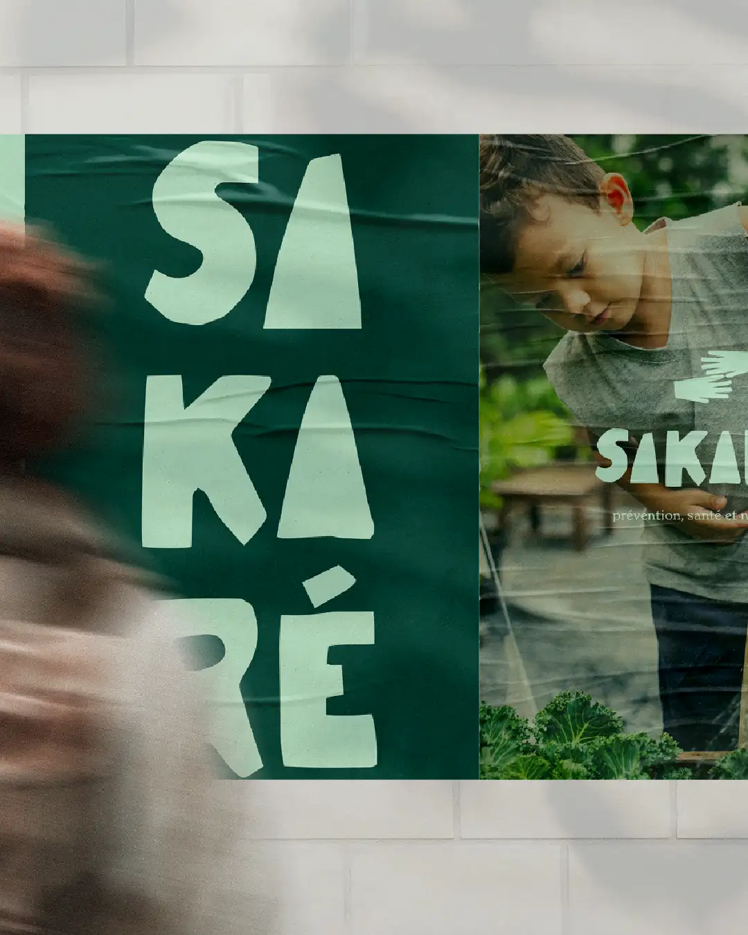 Sakaré dual street poster display: left light green SA-KA-RE stacked vertical typography on deep green, right child caring for plant with stylized green tones, blurred walking woman motion