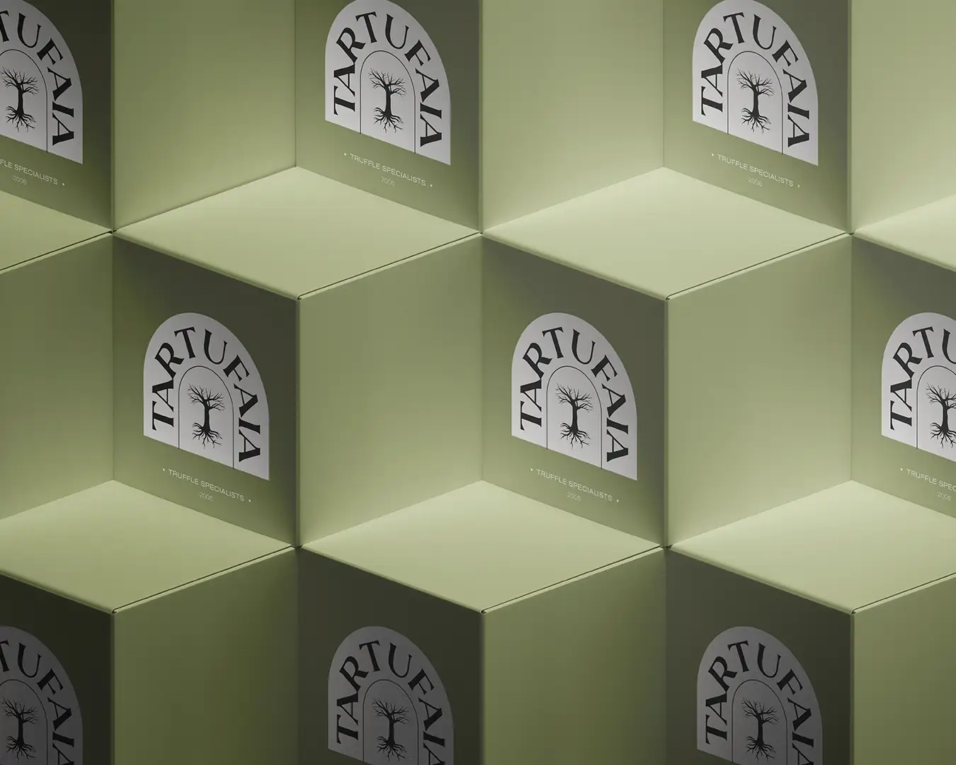 Gros plan sur une pile de packagings vert olive de la marque de truffes artisanales TARTUFAIA, avec logo noir couleur truffe sur le devant ; branding Studio La Folie.